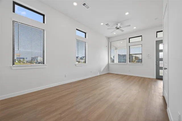 a view of empty room with wooden floor and fan