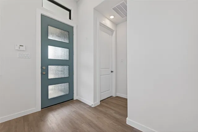 a view of an empty room and wooden floor and a window