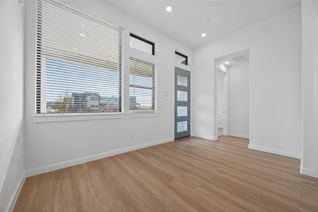 a view of an empty room with wooden floor and a window
