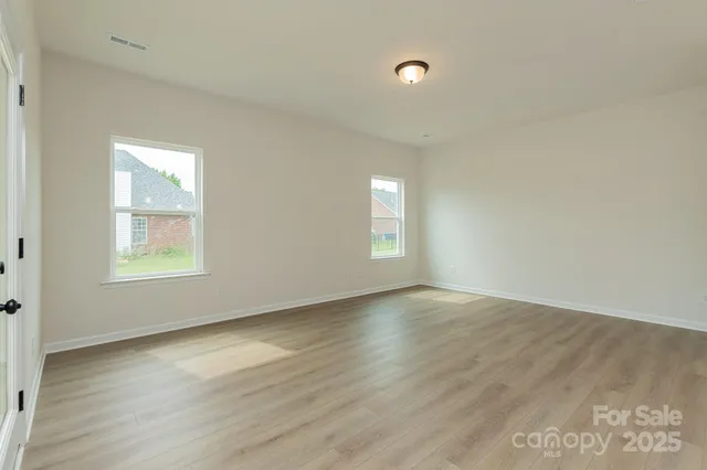 a view of an empty room with window and wooden floor