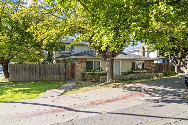 a front view of a house with a garden and trees