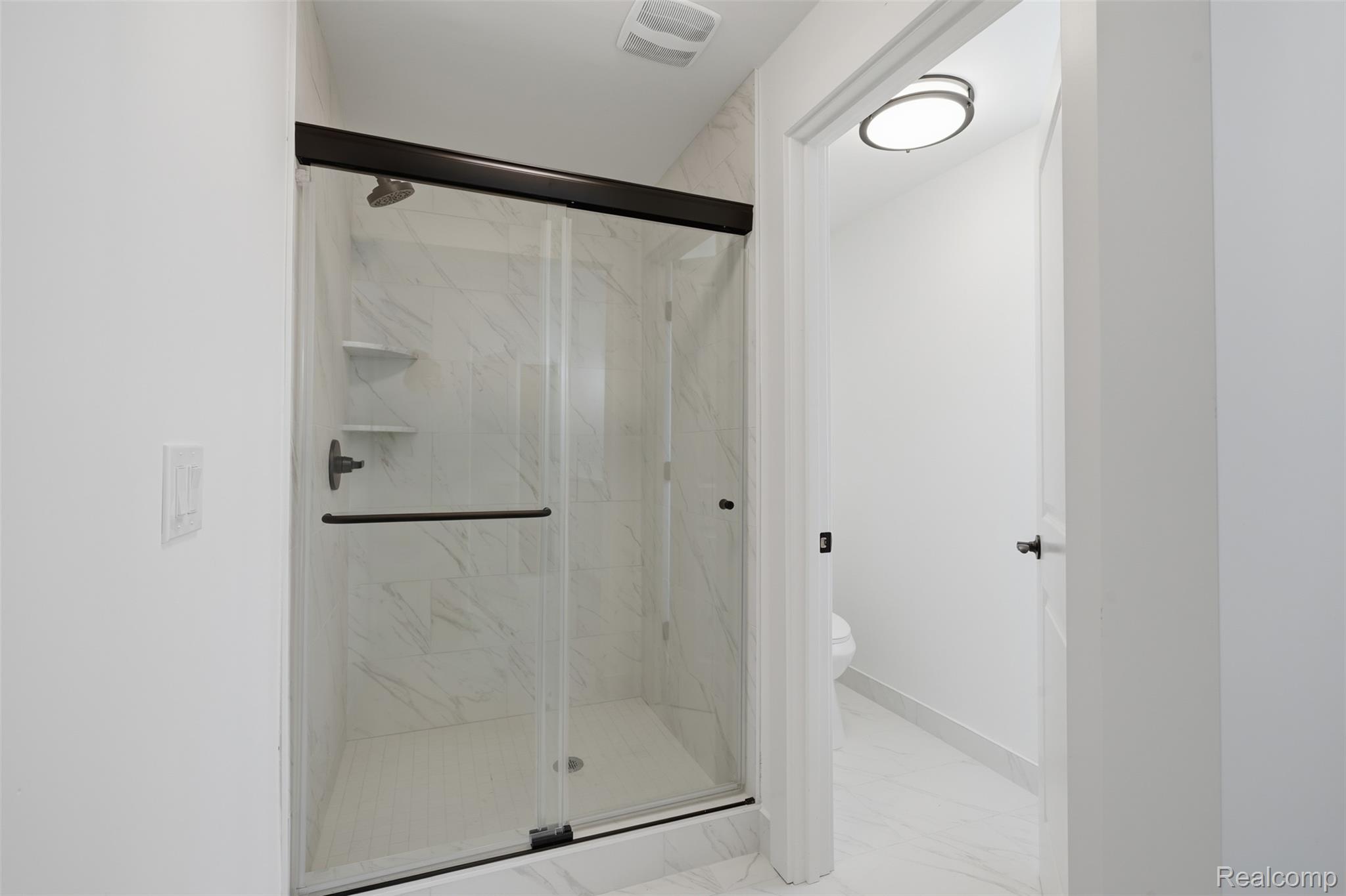 4655 Denton Road Canton, MI 48188 - Photo 27 of 54 Glass-enclosed shower with dark bronze hardware, white tile surround, and built-in shelving