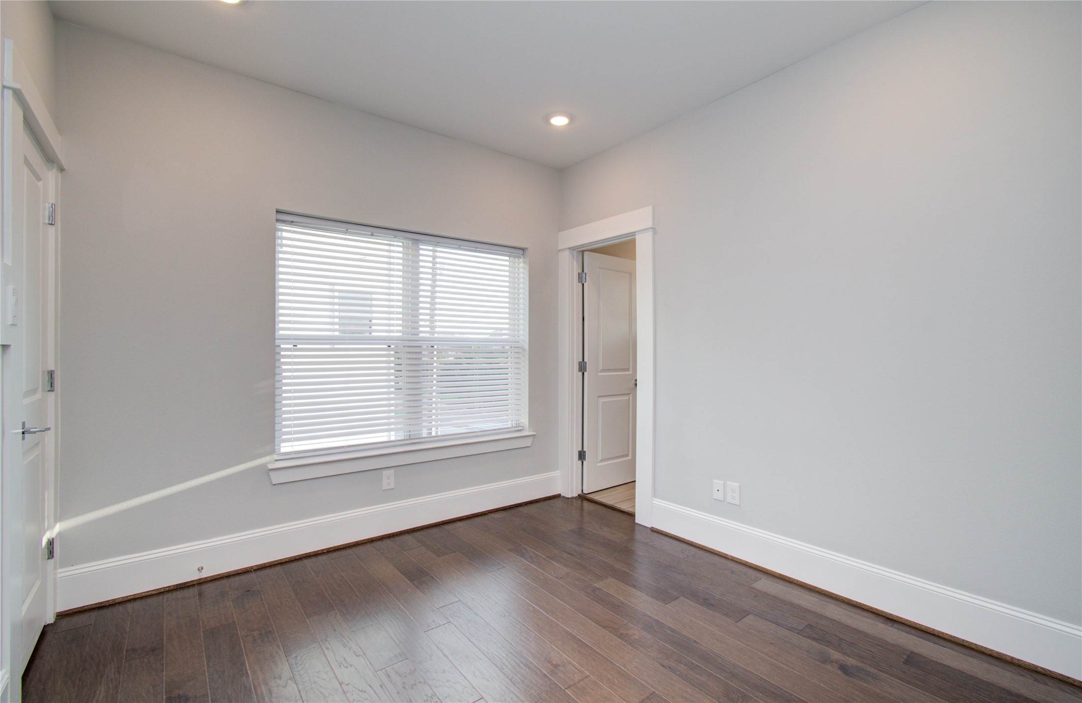 1262 North Post Oak Road, Unit A Houston, TX 77055 - Photo 31 of 50 This bright bedroom includes a double window fitted with white horizontal blinds for light control. Clean white trim along the baseboards and door frames contrasts neatly with the dark wood floor.