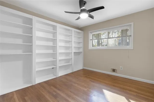 a view of empty room with wooden floor and fan