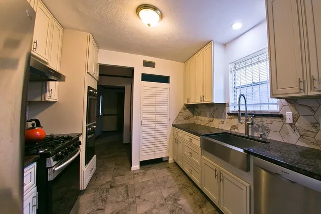 a kitchen with stainless steel appliances granite countertop a sink a stove and a refrigerator
