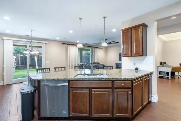 a kitchen with kitchen island granite countertop a sink a counter space appliances and cabinets