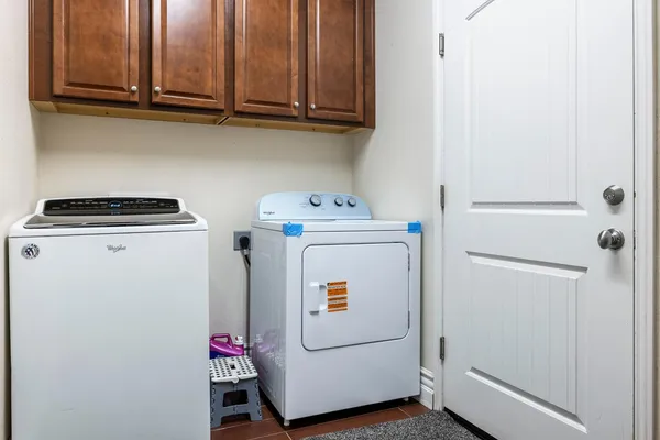 a utility room with dryer washer and wooden cabinets