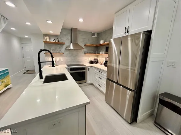 a kitchen with stainless steel appliances a refrigerator a sink a stove and white cabinets