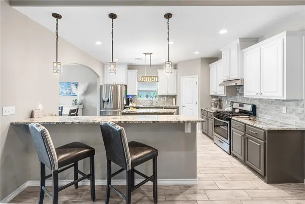 a kitchen with stainless steel appliances granite countertop a stove a sink a island with a dining table and chairs