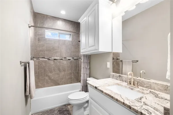 a bathroom with a granite countertop sink toilet and shower