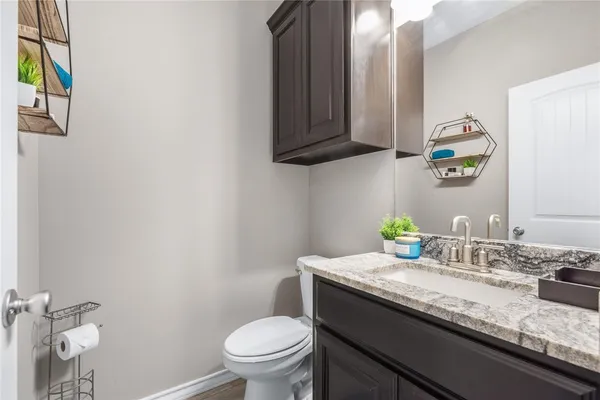 a bathroom with a granite countertop toilet sink and mirror