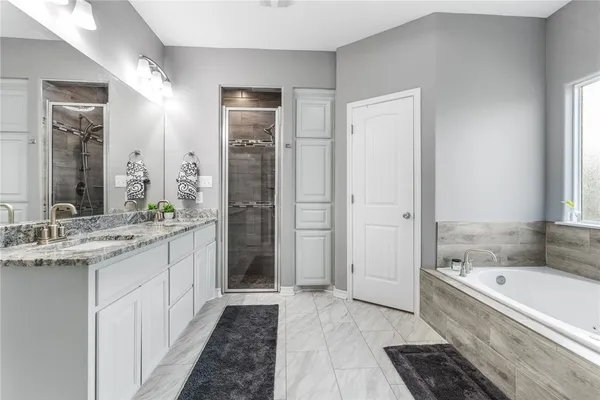 a bathroom with a granite countertop tub sink shower and mirror