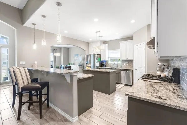 a kitchen with granite countertop kitchen island stainless steel appliances a sink a counter top space a center island stainless steel appliances and cabinets