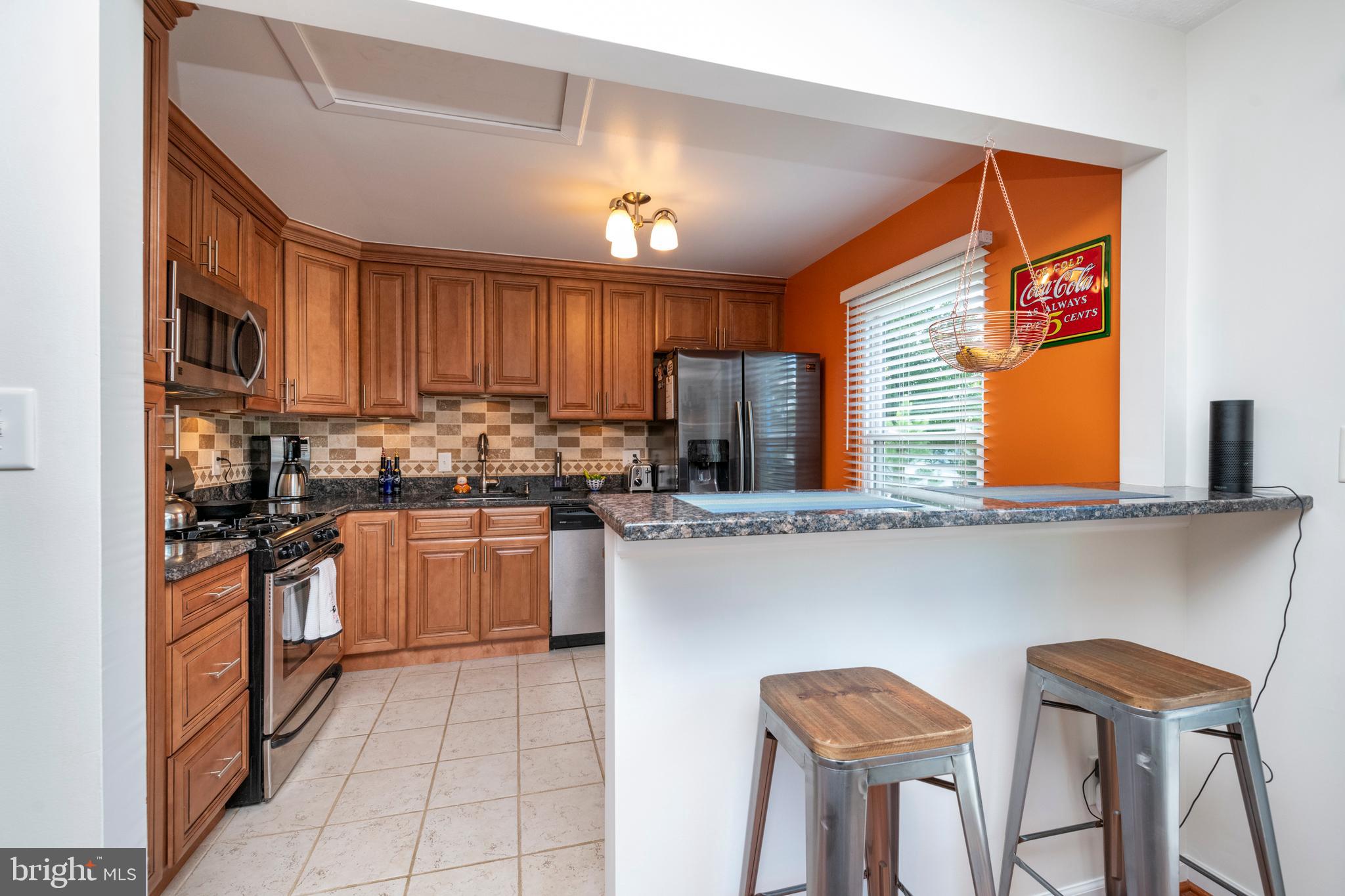 5014 Tartan Hill Road Perry Hall, MD 21128 - Photo 11 of 43 a kitchen with stainless steel appliances granite countertop a stove top oven a sink dishwasher a dining table and chairs with wooden floor