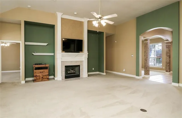 a view of a livingroom with a fireplace a chandelier and windows