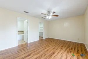 an empty room with wooden floor and a ceiling fan