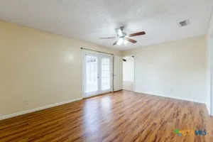 a view of an empty room with window and wooden floor