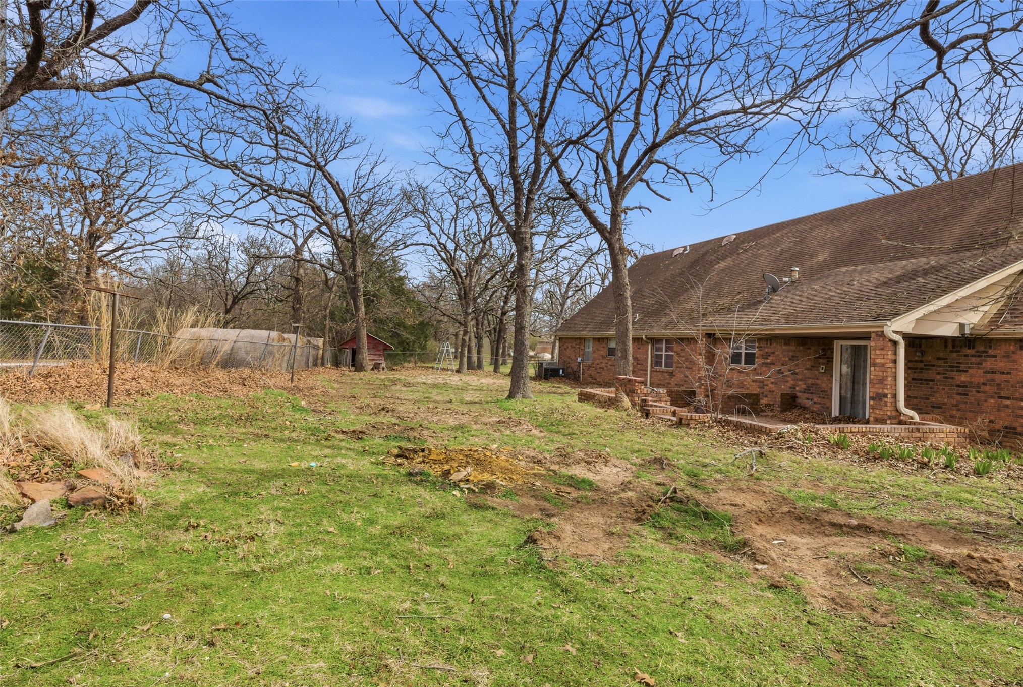 17875 East 589 Road Inola, OK 74036 - Photo 72 of 73 Expansive outdoor space featuring a sloped lawn, mature trees, and a brick-sided residence with multiple windows and a rear entry