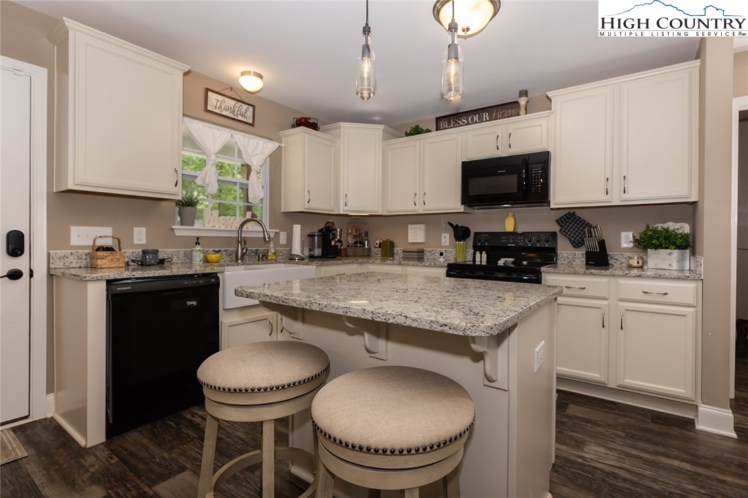 351 Colony Lane Purlear, NC 28665 - Photo 25 of 39 a kitchen with stainless steel appliances granite countertop a sink dishwasher a stove a microwave oven a refrigerator with white cabinets and wooden floor