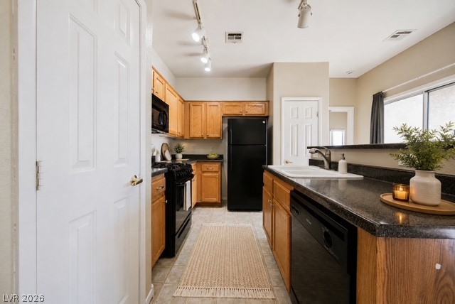 6320 Snap Ridge Street, Unit 201 North Las Vegas, NV 89081 - Photo 2 of 56 A galley kitchen boasts dark countertops, wooden cabinetry, and track lighting illuminating the space.