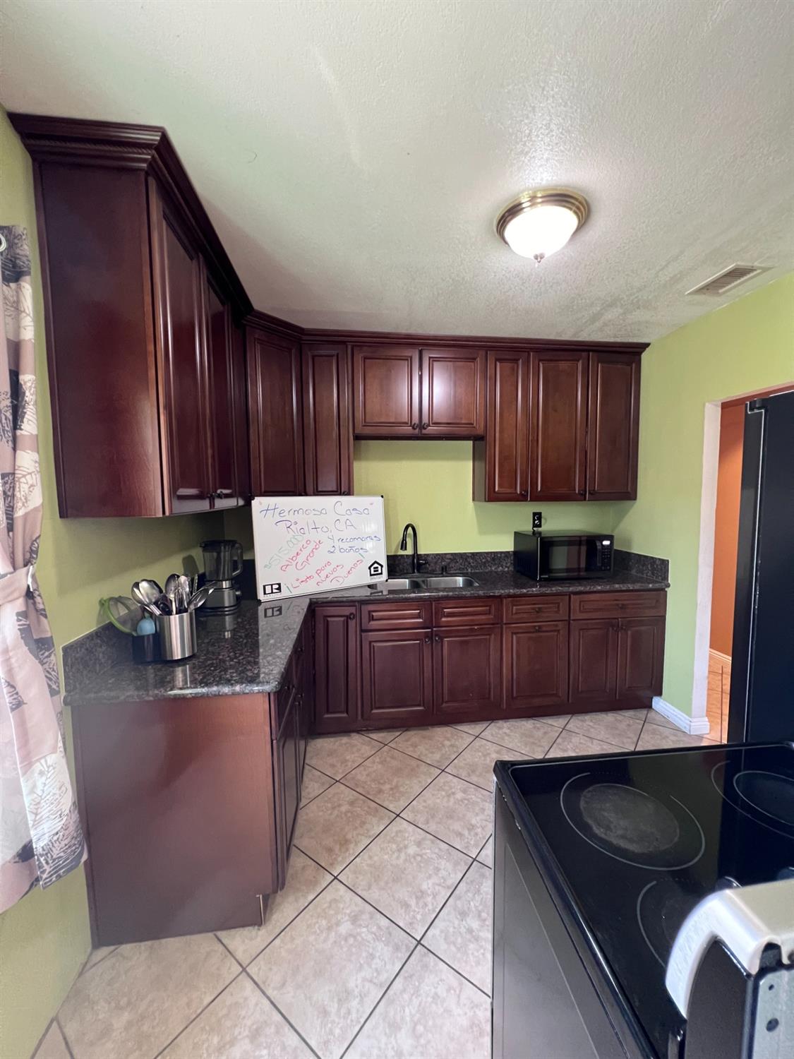 281 West Wilson Street Rialto, CA 92376 - Photo 5 of 15 a kitchen with granite countertop wooden cabinets a stove a sink and a refrigerator