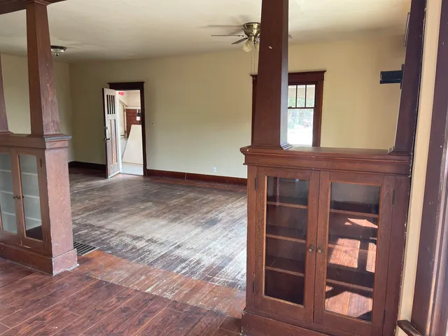 a view of an empty room with wooden floor and a window
