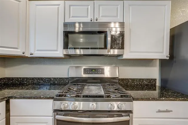 a kitchen with kitchen island granite countertop stove top oven and cabinets