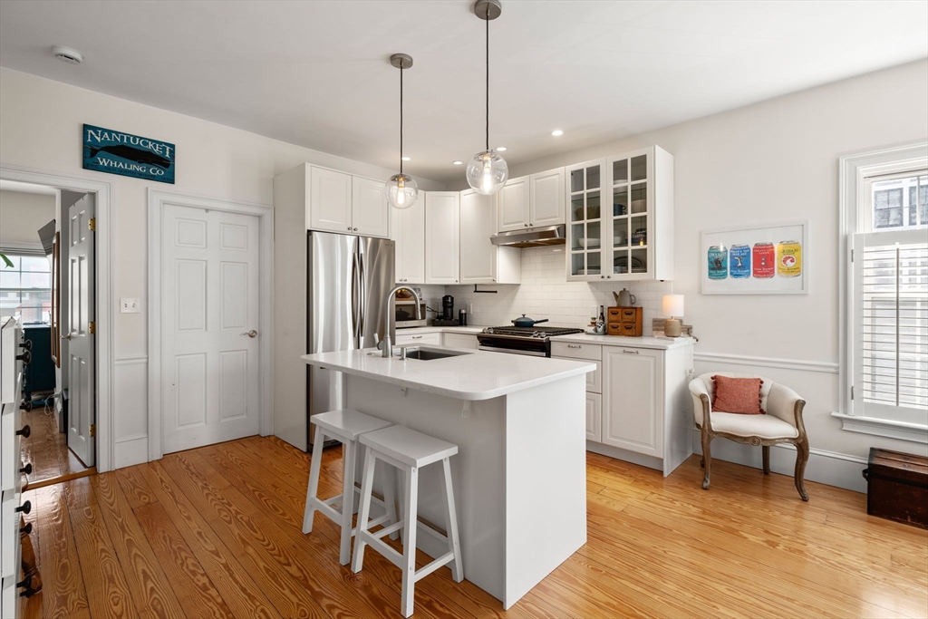 614 East 3rd Street, Unit 1 Boston, MA 02127 - Photo 2 of 23 a kitchen with stainless steel appliances granite countertop a stove a refrigerator a kitchen island a dining table and chairs with wooden floor