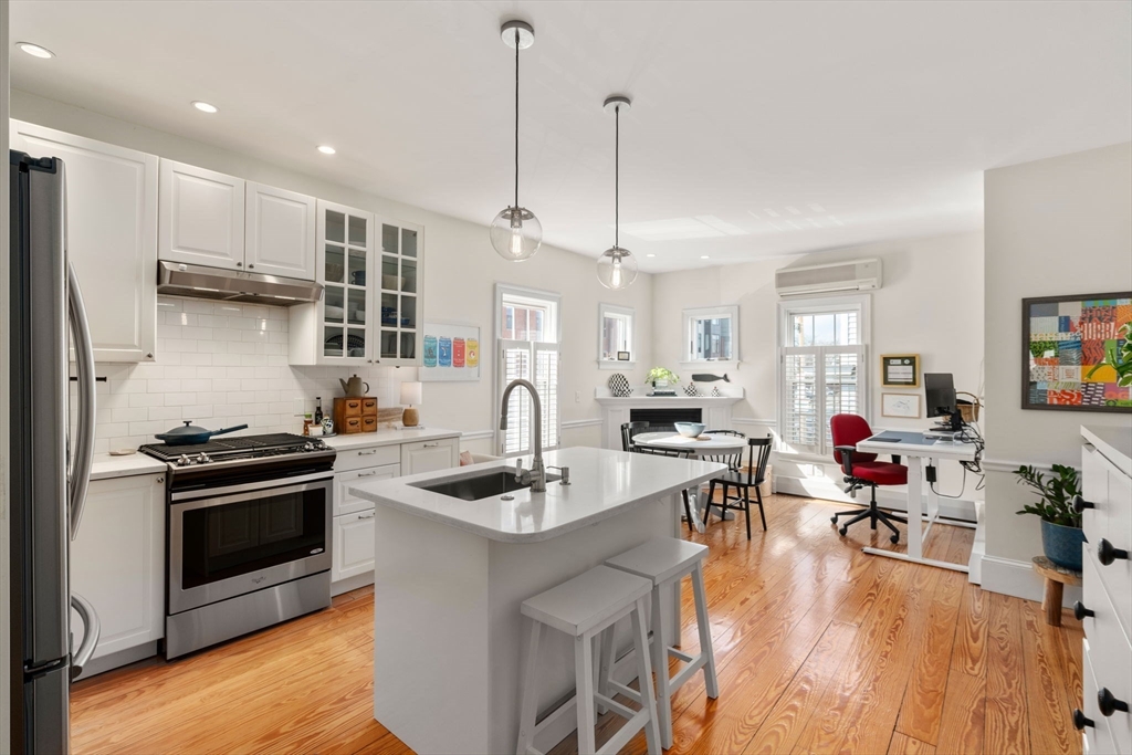 614 East 3rd Street, Unit 1 Boston, MA 02127 - Photo 4 of 23 a kitchen with stainless steel appliances granite countertop a stove refrigerator and couches with wooden floor