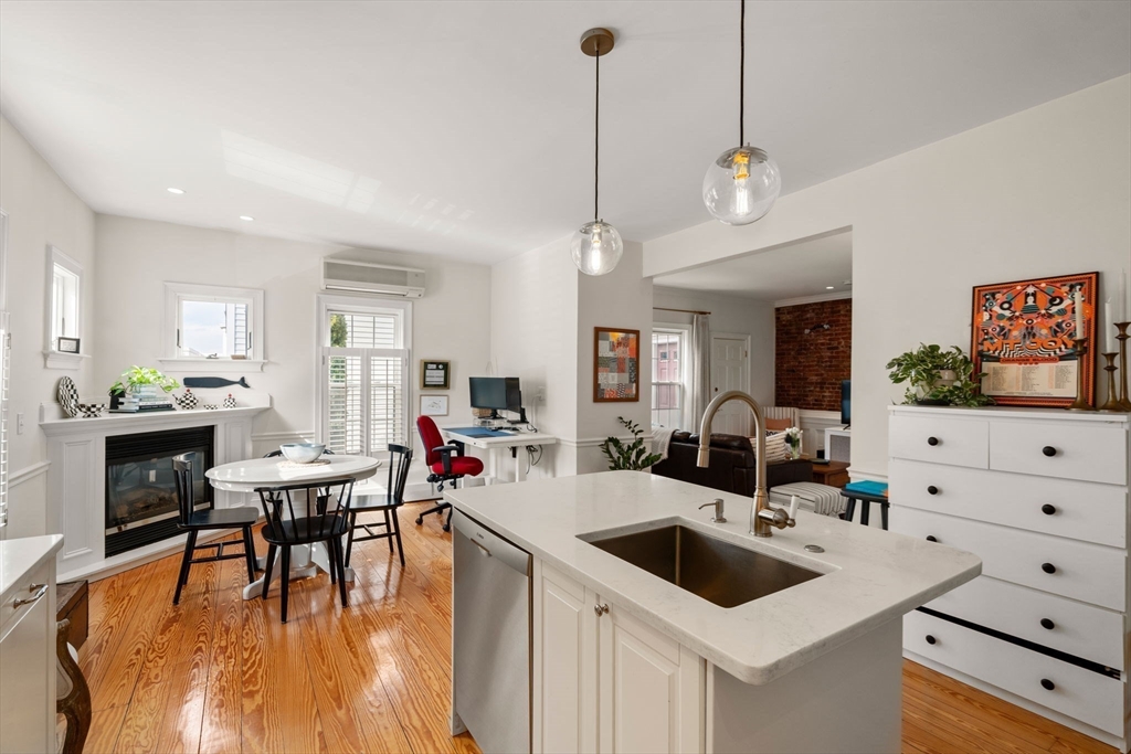 614 East 3rd Street, Unit 1 Boston, MA 02127 - Photo 5 of 23 a view of a dining room and livingroom with furniture wooden floor a rug a fireplace and a chandelier