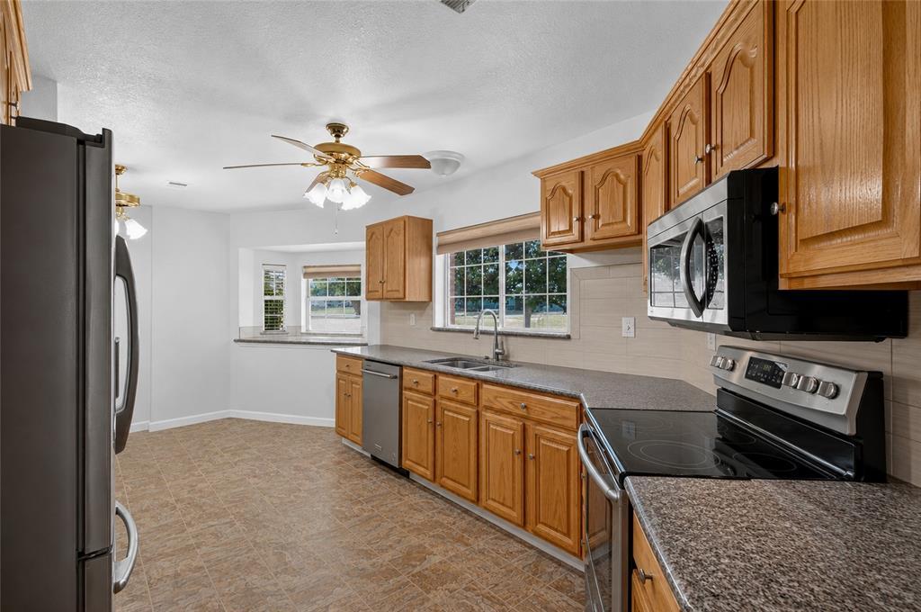 1612 Whitemound Road Sherman, TX 75090 - Photo 6 of 28 Kitchen featuring wood cabinetry, granite-patterned countertops, stainless steel appliances, and a bay window