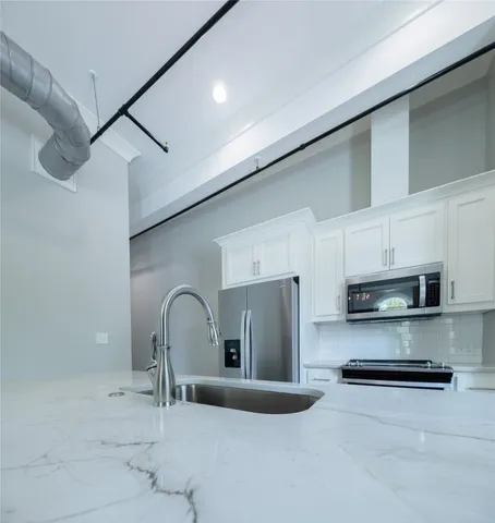 a kitchen with stainless steel appliances granite countertop a sink a stove and a refrigerator