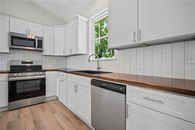 a kitchen with stainless steel appliances granite countertop white cabinets a sink and dishwasher