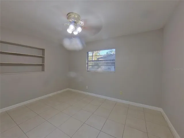 an empty room with a chandelier fan and windows