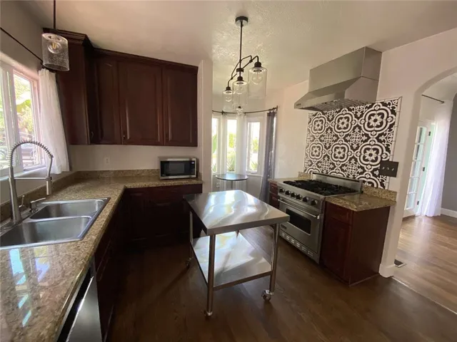 a kitchen with granite countertop a stove a sink and a wooden cabinets