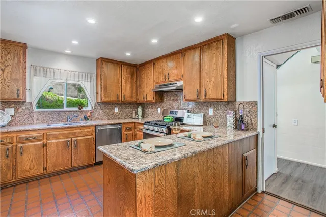 a kitchen with stainless steel appliances granite countertop wooden cabinets a sink and a stove