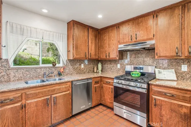 a kitchen with stainless steel appliances granite countertop a sink stove and cabinets