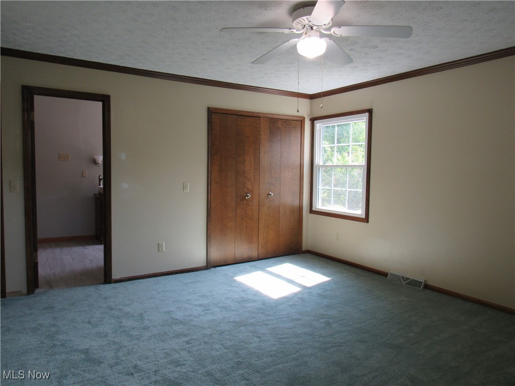 1120 Vincent Road Southeast North Canton, OH 44720 - Photo 34 of 50 Owner's suite bedroom with a textured ceiling, new carpet, ceiling fan, and double closets