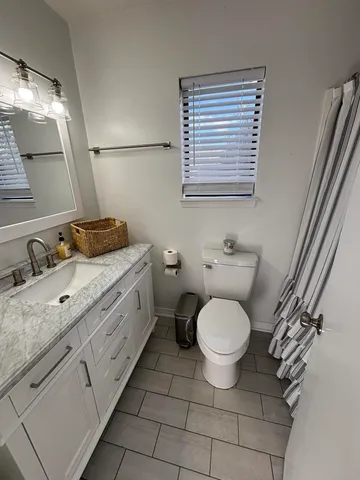 a bathroom with a granite countertop toilet sink and mirror