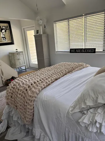 a bedroom with a bed and a large mirror next to a window