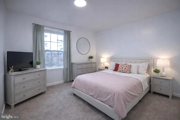 a bedroom with a bed and a flat tv screen on dresser