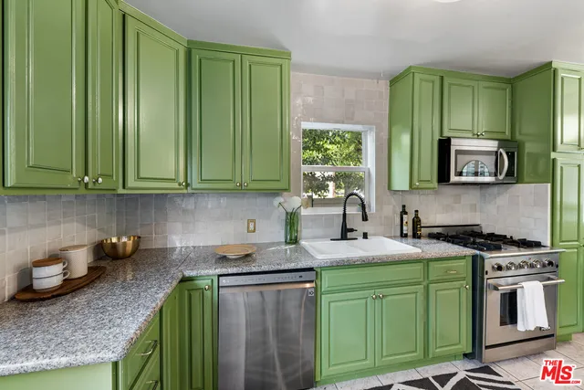 a kitchen with stainless steel appliances granite countertop a sink a stove a microwave cabinets and a refrigerator