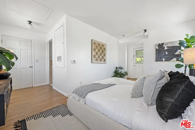 a large bed sitting in a bedroom next to a lamp with a potted plant on a table