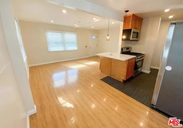 a kitchen with stainless steel appliances a refrigerator sink and wooden floor