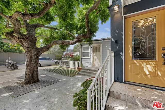 a yellow house with large trees in front of it