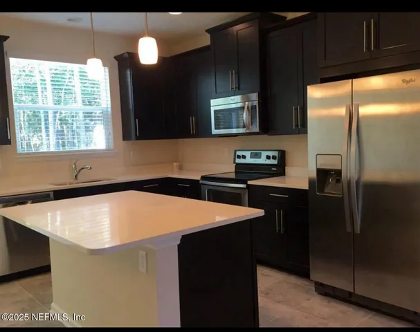 a kitchen with stainless steel appliances granite countertop a sink a stove and a refrigerator