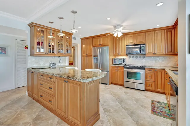 a dining hall with stainless steel appliances kitchen island granite countertop a table and chairs in it