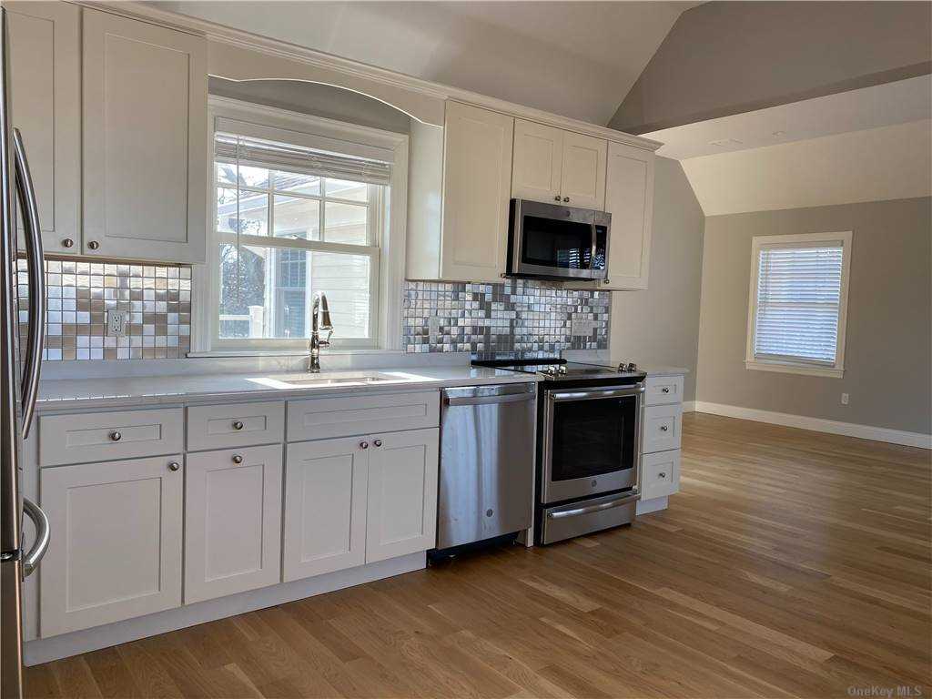 159 Mill Road, Unit C Westhampton Beach, NY 11978 - Photo 1 of 1 a kitchen with stainless steel appliances a stove microwave and sink