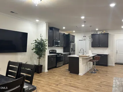 a kitchen with stainless steel appliances kitchen island granite countertop a stove top oven a sink a dining table and chairs