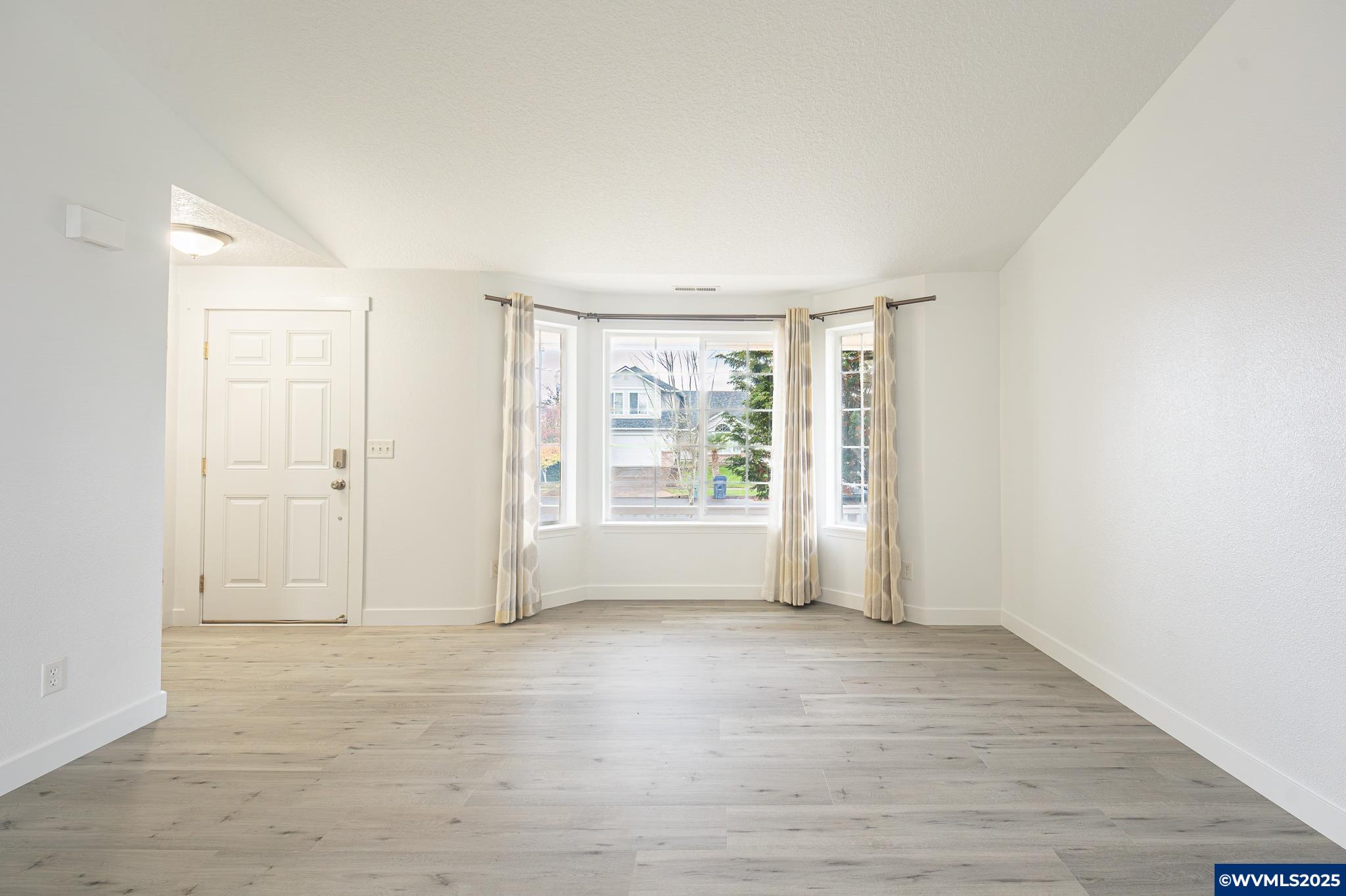 1467 South 7th Street Independence, OR 97351 - Photo 4 of 31 an empty room with wooden floor and windows with curtains
